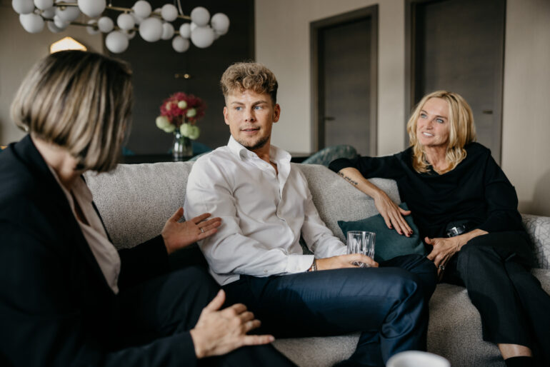 2 Frauen und ein Mann unterhalten sich am Sofa