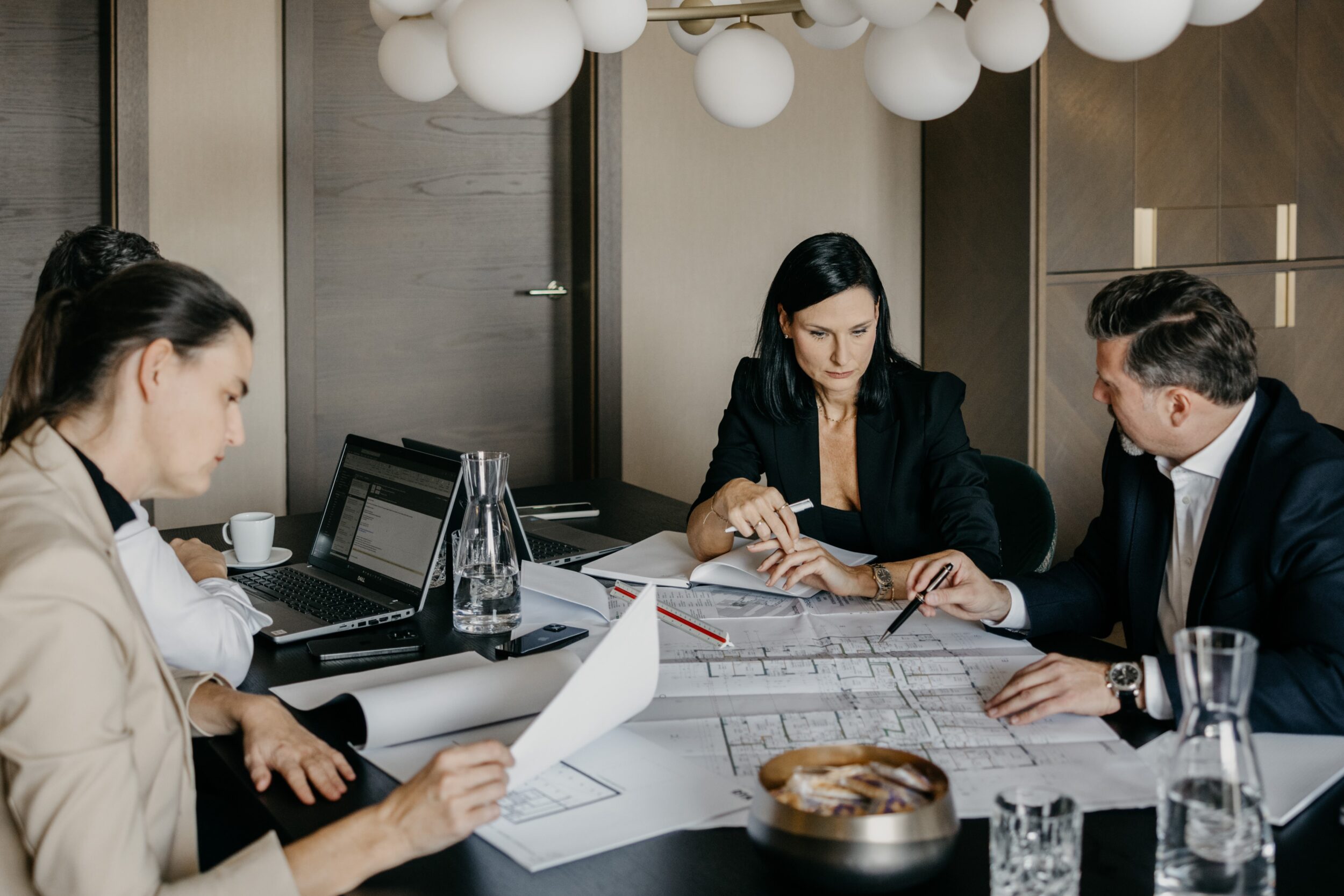 2 Frauen und ein Mann im Büro bei einer Besprechung mit Plänen